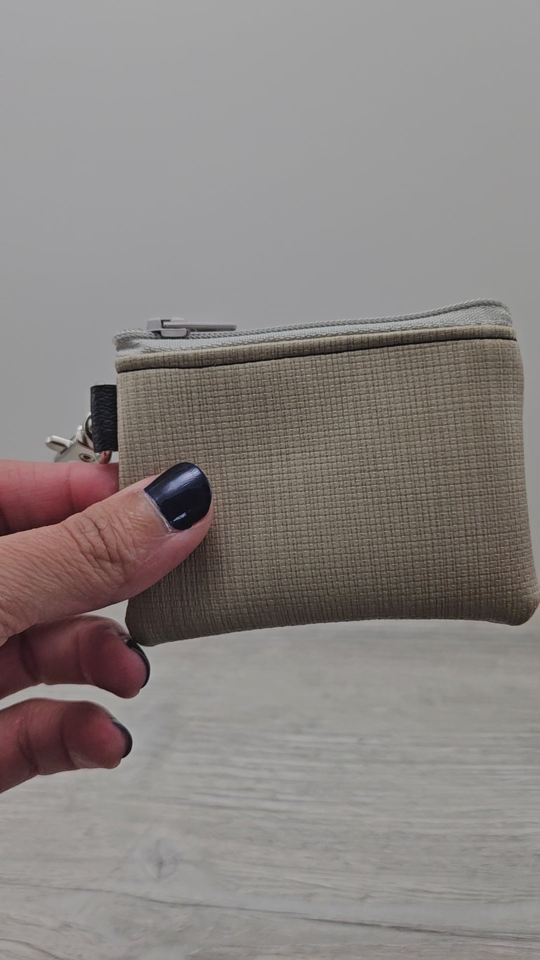 Video of mini beige, vinyl zipper pouch with swivel clasp.