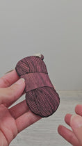 Load and play video in Gallery viewer, Video of yarn skein ornament laser cut and engraved from exotic purpleheart wood.
