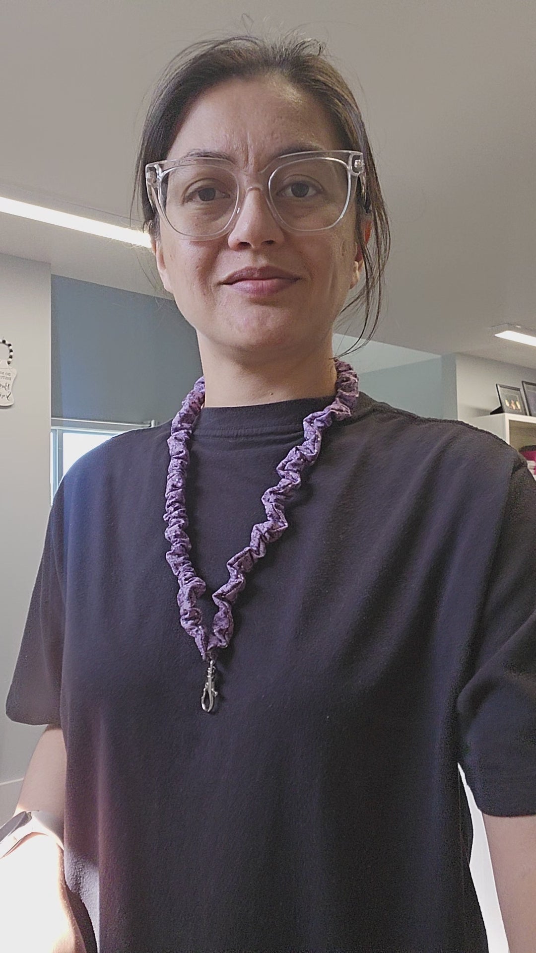 Short video of a person wearing a black shirt and a purple skinny scrunchie lanyard.