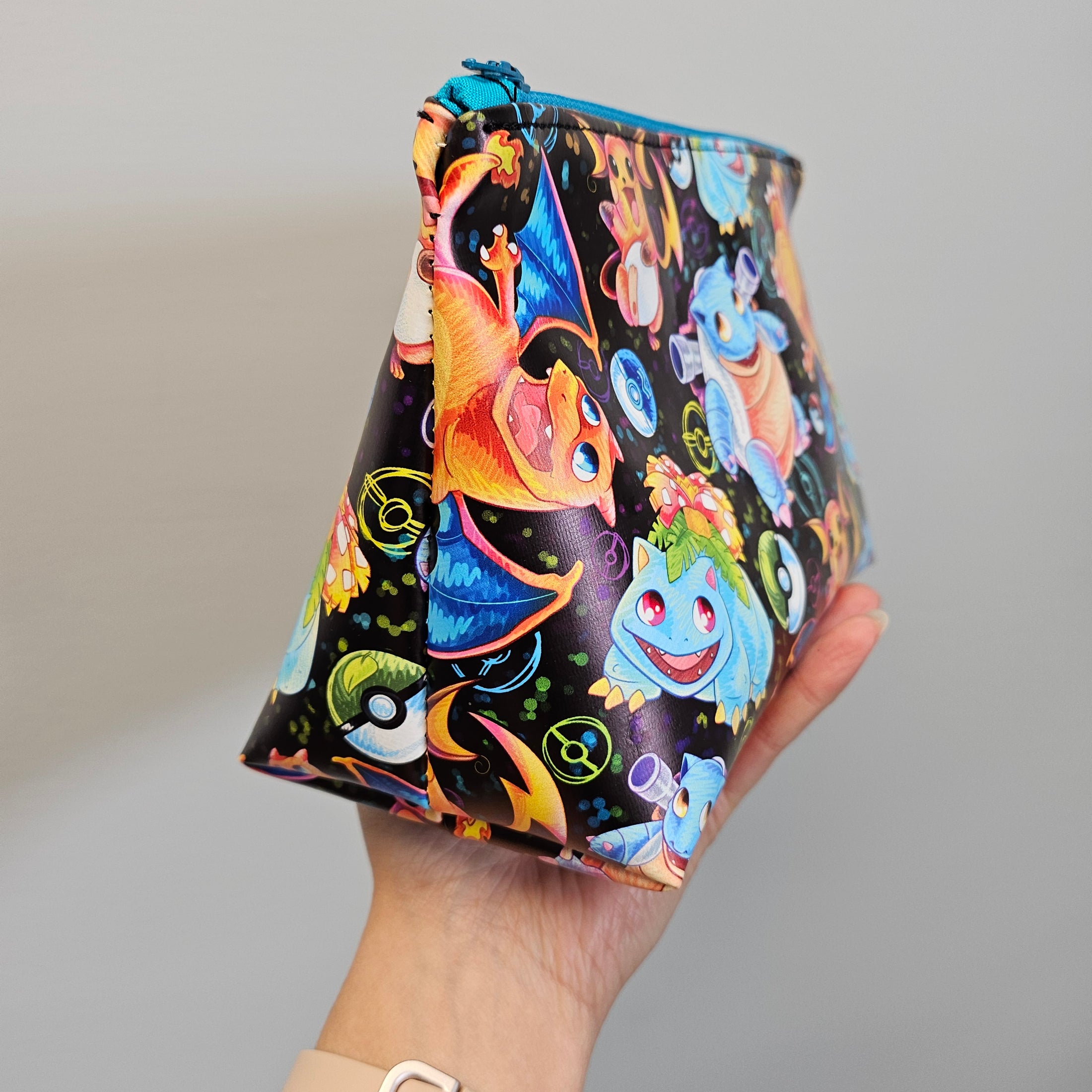 Colorful drawstring bag with cartoon characters held by a hand against a gray background