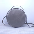 Load image into Gallery viewer, Front of taupe faux leather round purse. 
